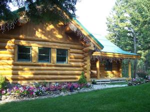 una cabaña de madera con flores delante en The Garrison Inn a Montana Bed & Breakfast, en Kalispell