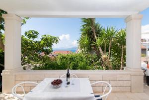 un tavolo bianco con una bottiglia di vino sul balcone di Apartments Veve a Postira (Postire)