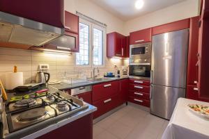 una cocina con armarios rojos y electrodomésticos de acero inoxidable en Virginia's Art House, en Porto Rafti 37 fotos más