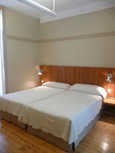 1 dormitorio con 1 cama grande con sábanas blancas en Las Carolinas Garden, en Santander