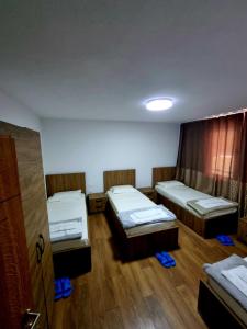a room with three beds in it with wooden floors at Guesthouse Rama in Valbonë