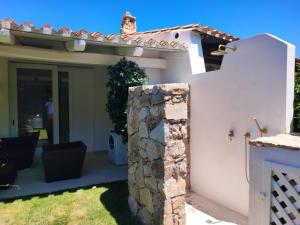 a white house with a stone pillar in the yard at Capo Ceraso Family Resort in Costa Corallina