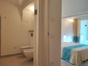 a bedroom with a bed and a bathroom with a toilet at Capo Ceraso Family Resort in Costa Corallina