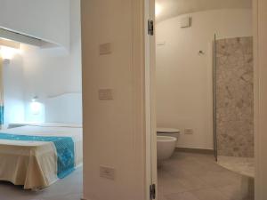 a bedroom with a bed and a bathroom with a toilet at Capo Ceraso Family Resort in Costa Corallina