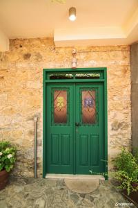 a green door with stained glass windows on a stone wall at Anastou's Traditional House in Kalopanayiotis