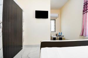 ein Zimmer mit einem Bett und einem Fernseher an der Wand in der Unterkunft Hotel O Shree Jagannath Residency in Khandagiri