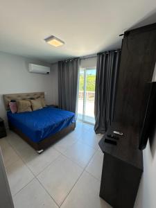 ein Schlafzimmer mit blauem Bett und Balkon in der Unterkunft Cobertura na praia in Arraial do Cabo + 3 Fotos