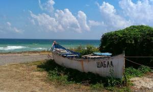a boat sitting on the side of a beach at Guest House Sunrise in Shabla