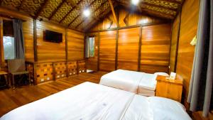 a bedroom with two beds in a room with wooden walls at Melrimba Garden in Tengahgirang