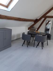 Un comedor con mesa y sillas en un ático. en LA BONNE ADRESSE, en La Neuville en Chaillois