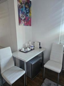 a desk with two white chairs and a table and a painting at SMB home PANORAMA in Oradea