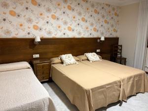 sypialnia z 2 łóżkami i ścianą z kwiatami w obiekcie Casa Fuentes w mieście Poio