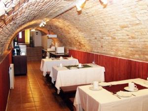 uma sala de jantar com mesas brancas e uma parede de tijolos em Decsi Vendégház em Esztergom
