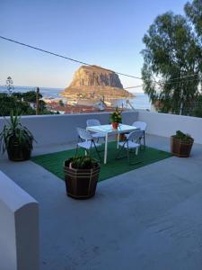 a table and chairs on a balcony with a mountain in the background at Golden Hour in Monemvasia