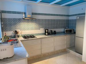 a kitchen with white cabinets and blue tiles on the wall at Habibi-Danydan La Chebba in Chebba