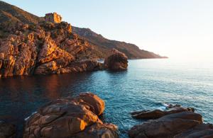 una vista di uno specchio d'acqua con rocce e un castello di Hôtel & Résidence Le Subrini a Porto Ota