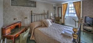 a bedroom with a bed and a desk and a television at Busta House Hotel in Busta