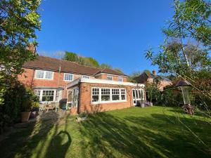 a large brick house with a lawn in front of it at Four bedroom Rural home in the South Downs in Linchmere