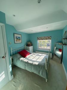a bedroom with a bed with blue walls and a window at Four bedroom Rural home in the South Downs in Linchmere