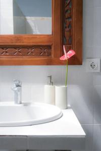 baño con lavabo y flor rosa en Uluwatu Beach Hidden Gem Apartment, en Uluwatu