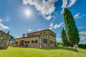 an old stone house with a tree in the foreground at Agriturismo Poggio Istiano in Bagno Vignoni