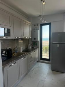a kitchen with white cabinets and a large window at ELIZ Luxury Residence in Mamaia