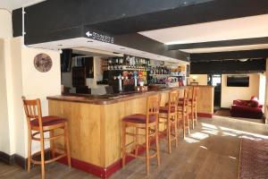 a bar with a row of wooden stools in a restaurant at The Sun Inn in Whitfield