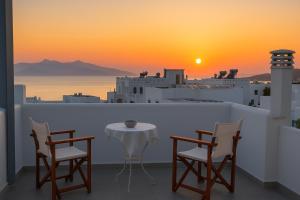 a table and chairs on a balcony with a sunset at Ale appartment in Agios Prokopios
