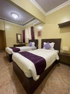 two beds in a hotel room with purple pillows at Hotel Manggala Syariah in Pacitan +24 photos