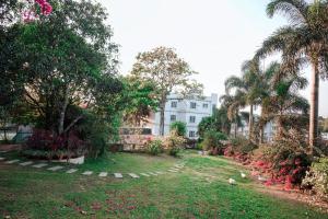 a yard with palm trees and a white building at Nigara Residency in Vandanmedu