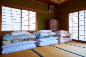 a room with a stack of pillows in a room with windows at guesthouse Emi 笑み NIKKO in Nikko