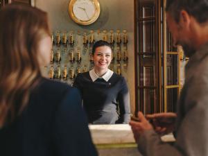 a woman is smiling in front of a mirror at Fairmont Hotel Vier Jahreszeiten in Hamburg