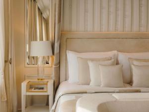 a bedroom with a white bed and a table with a lamp at Fairmont Hotel Vier Jahreszeiten in Hamburg