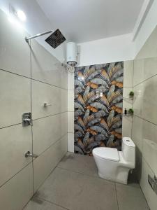 a bathroom with a toilet and a mural on the wall at VGK Residency in Wayanad