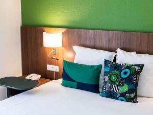 卡宴Ibis Styles Cayenne Centre Amazonia的卧室里有一张带绿色床头板的床和一部电话