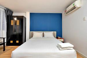 a bedroom with a white bed with a blue wall at S79 Residences SEN in Ho Chi Minh City