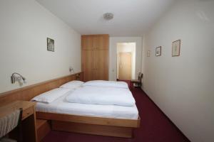 セルヴァ・ディ・ヴァル・ガルデーナにあるHotel Alpino Planのベッドルーム1室(白いシーツが備わるベッド2台付)