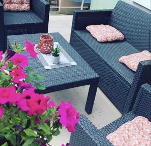 a patio with two blue wicker chairs and a table with flowers at Vila Plaza-1 in Bela Crkva +1 photo