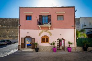 różowy dom z balkonem na ulicy w obiekcie Casa Vacanze Cappuccini w mieście Castellammare del Golfo