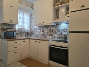 a kitchen with white cabinets and a stove top oven at La Casa di Levante in Zakynthos