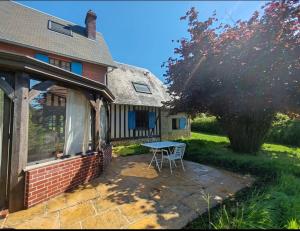 a patio with a table in front of a house at La maison bleue in Reux