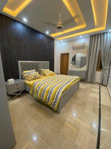 a bedroom with a bed with a yellow comforter and a mirror at Johar Guesthouse-Suite 3Bed and Lounge in Karachi in Karachi
