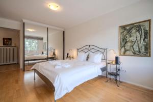 a bedroom with a large white bed and a mirror at Irmella 39 by Arosa Vacations, mit Pool & Sauna in Arosa