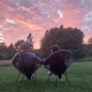ein Mann und eine Frau sitzen auf Stühlen auf einem Feld in der Unterkunft Jaagu Metsatelk neljale in Suuremõisa