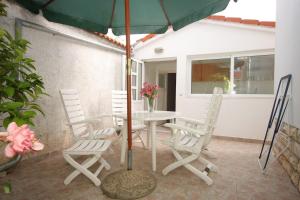 a patio with a table and chairs and an umbrella at Apartment GRANDE in Preko