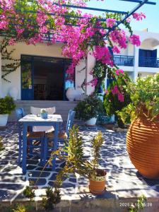 patio con tavolo e alcuni fiori rosa di Hotel Flisvos a Megalochori (Isola di Agistri)