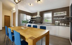 a kitchen with a wooden table and blue chairs at Beautiful Home In Kunj With Wifi in Kunj