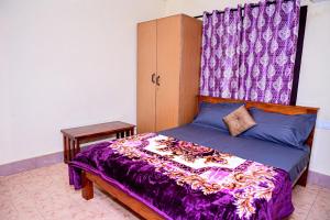 a bedroom with a bed with a purple comforter at Coorg mansion in Madikeri