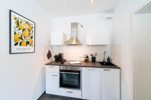 a kitchen with white cabinets and a stove top oven at Deluxe Koblenz Flat, Parken, Netflix, Ruhig in Bendorf +5 photos