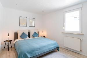 a bedroom with a bed with blue sheets and a window at Deluxe Koblenz Flat, Parken, Netflix, Ruhig in Bendorf